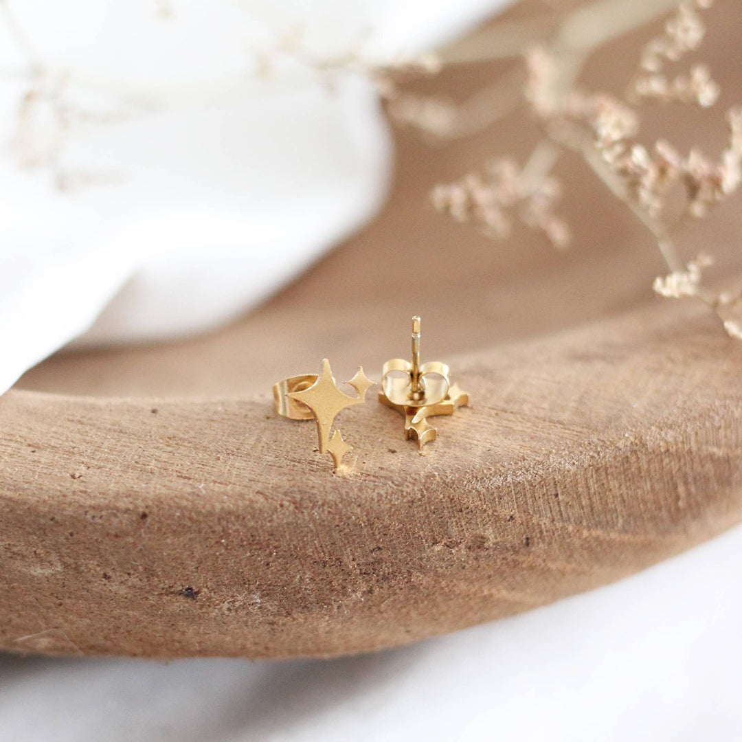Gold star-shaped earrings on a wooden surface