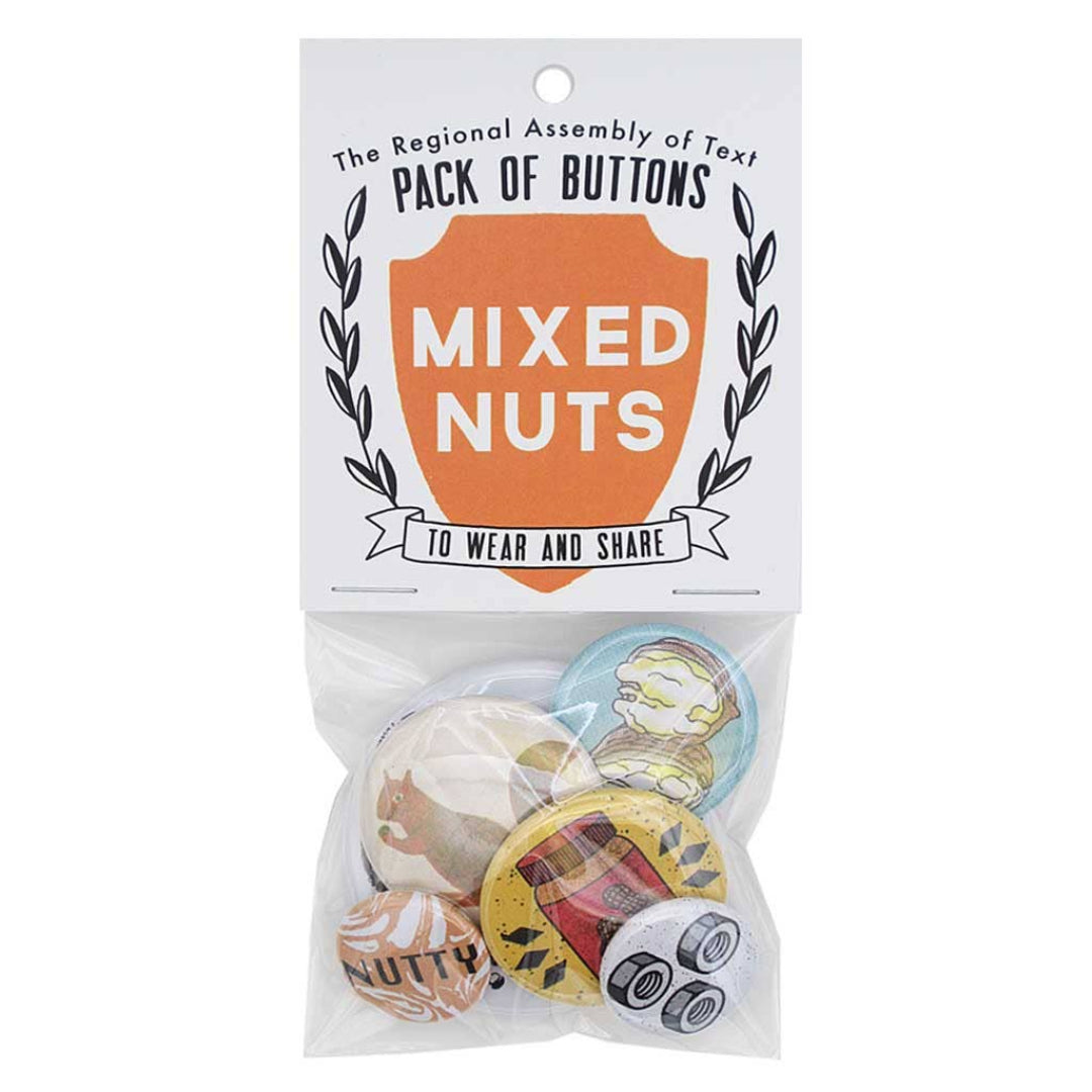 A clear plastic package containing six buttons with a "Mixed Nuts" theme. The header card reads "The Regional Assembly of Text PACK OF BUTTONS" and features a shield with "MIXED NUTS" inside, and "TO WEAR AND SHARE" below. Visible buttons include a squirrel, a jar of peanut butter, and two nuts and bolts designs.