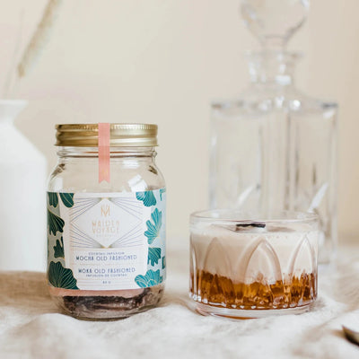 A glass jar filled with dried orange slices, cocoa nibs, and other ingredients. The jar has a white label with the Maiden Voyage logo and the product name 