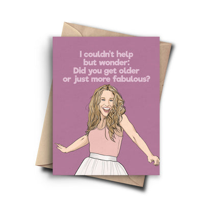 A humorous birthday card featuring a cartoon drawing of Sarah Jessica Parker as Carrie Bradshaw, wearing a tank top and a flowing skirt. The text on the purple background reads, 