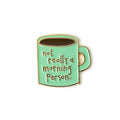 Enamel pin of a green mug with 'not really a morning person' text on a white background