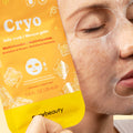 A close-up of a person wearing a translucent jelly face mask while holding a bright orange and yellow Cryo Jelly Mask packet. The packet features ice cube graphics and the brand name 'mrybeauty' at the bottom.