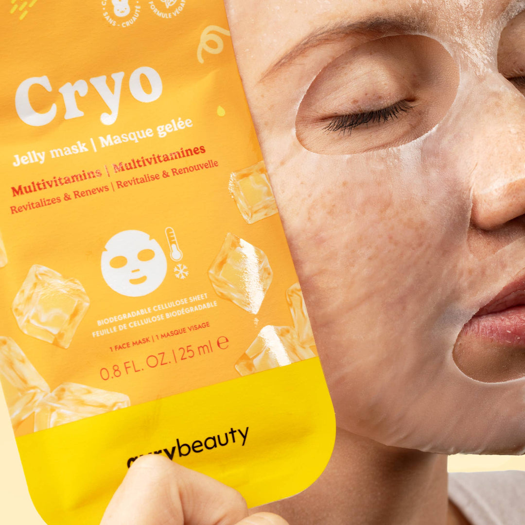 A close-up of a person wearing a translucent jelly face mask while holding a bright orange and yellow Cryo Jelly Mask packet. The packet features ice cube graphics and the brand name 'mrybeauty' at the bottom.