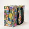 A large, reusable tote bag with a mushroom pattern. The bag is olive green with black handles. It is covered in a variety of colorful mushrooms in different shapes and sizes.