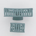 Two teal-colored hair clips on a light gray background