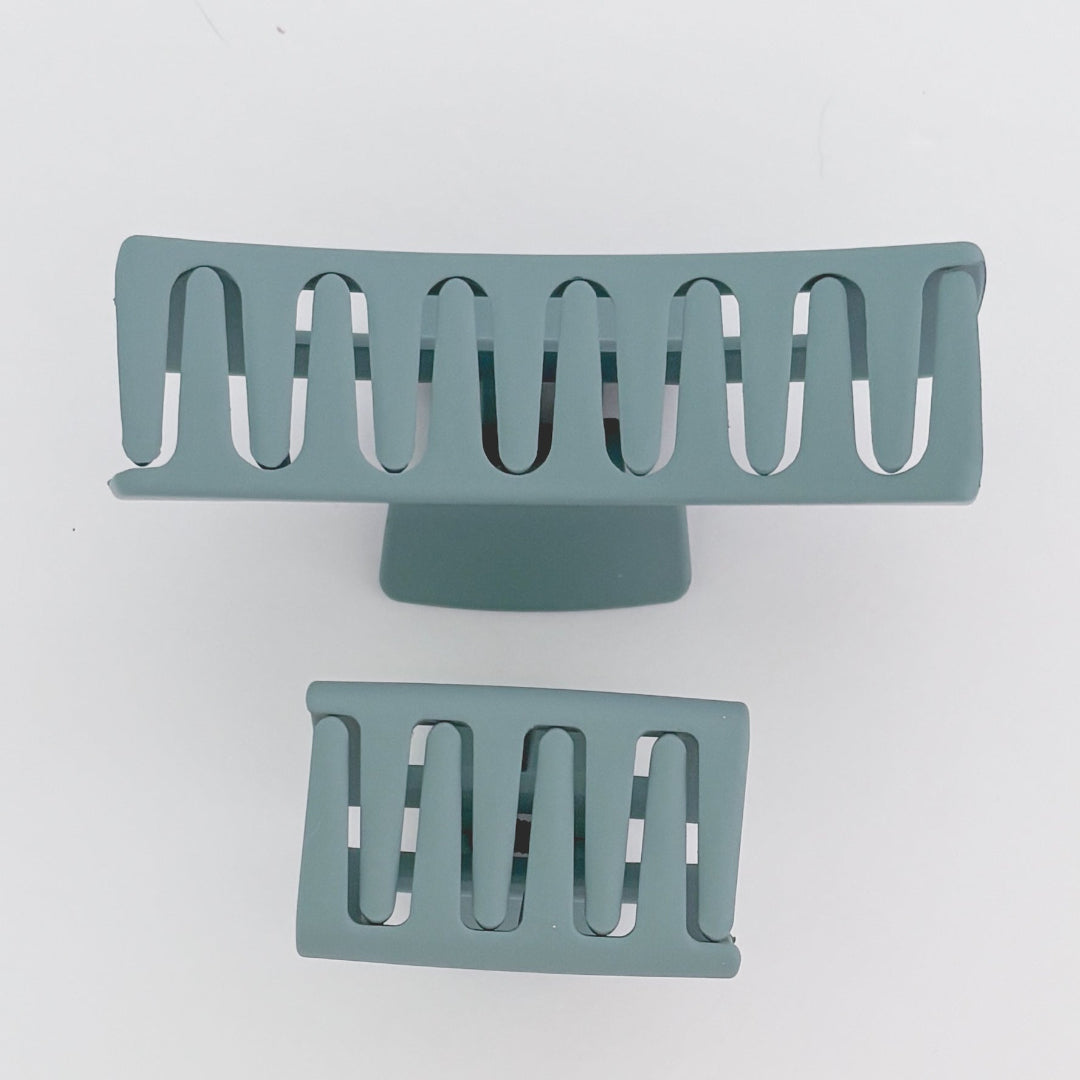 Two teal-colored hair clips on a light gray background
