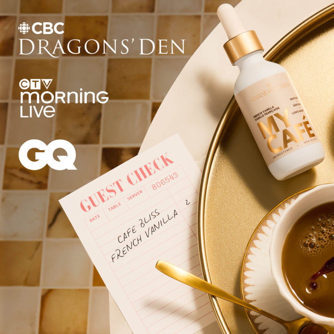 A styled flat-lay featuring a white cosmetic bottle with a gold dropper cap labeled 'MY CAFE' on a gold tray, alongside a cup of coffee, a guest check pad, and promotional text for CBC Dragons' Den, OTB Morning Live, and GQ.