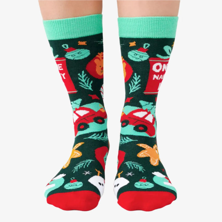 A pair of festive socks with a Christmas theme. The socks are green with red and white accents. One sock features the phrase 