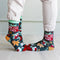 A pair of festive socks with a Christmas theme. The socks are green with red and white accents. One sock features the phrase 