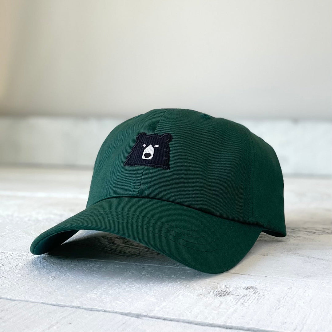 Green cap with a black bear logo on a light wooden surface