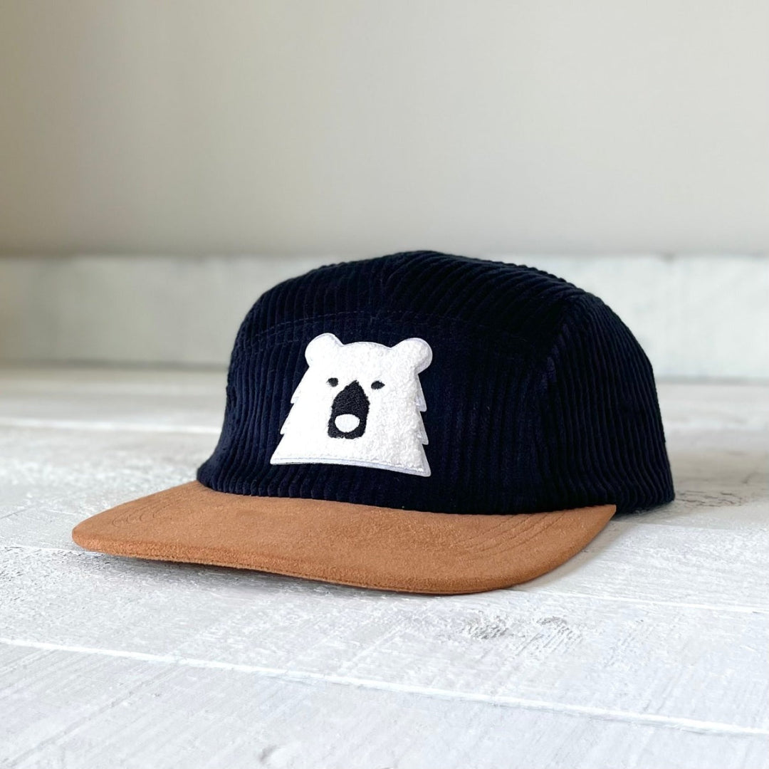 Navy blue cap with brown visor and white bear logo on a light gray surface