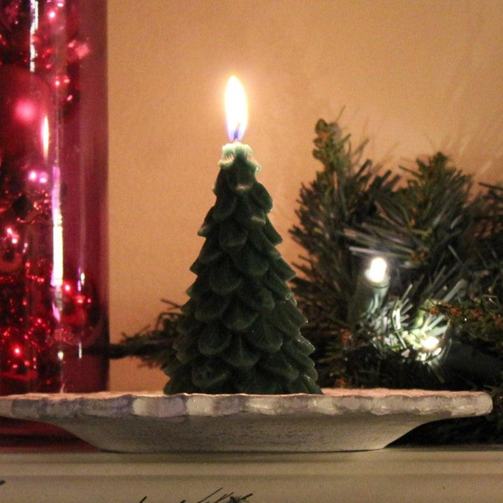 A green, beeswax candle shaped like a Christmas tree. The candle has detailed branches and a pointed top.