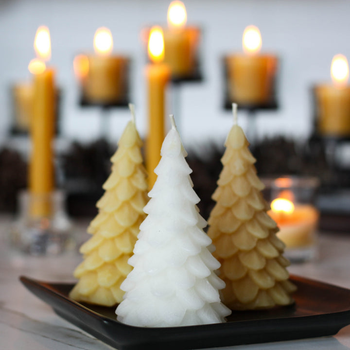 A yellow, beeswax candle shaped like a Christmas tree. The candle has detailed branches and a pointed top.