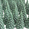 A green, beeswax candle shaped like a Christmas tree. The candle has detailed branches and a pointed top.