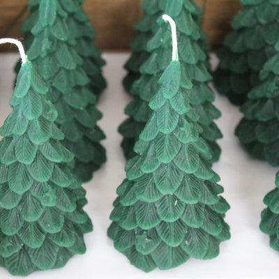A green, beeswax candle shaped like a Christmas tree. The candle has detailed branches and a pointed top.