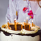 A chocolate cake with white frosting and yellow beeswax candles lit on top.