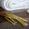 A cardboard box of birthday candles open on a wooden surface. The candles are yellow beeswax and are spilling out of the box. In the background, there is a white towel.