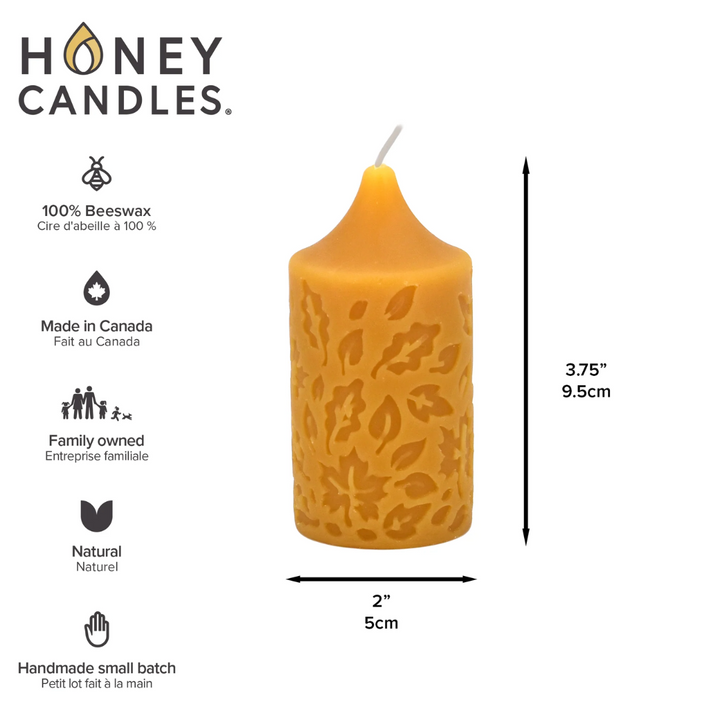 A yellow beeswax pillar candle with a leaf pattern. The candle has a label that says 