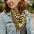 Woman wearing a green patterned scarf and denim jacket outdoors