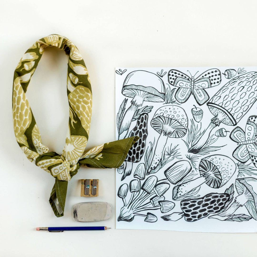 Green patterned headscarf, coloring book with mushroom design, and coloring supplies on a white background