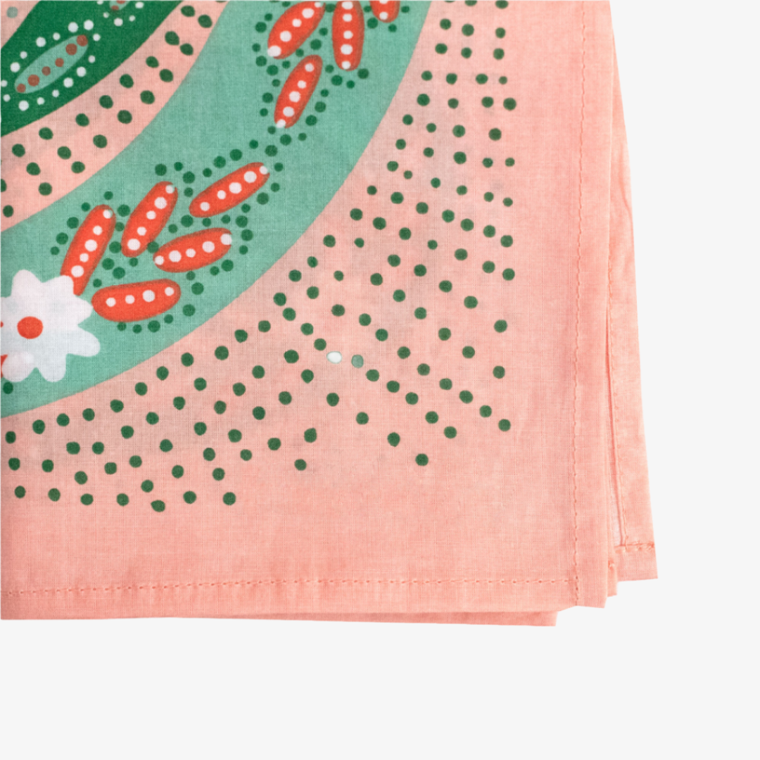 Close-up of a pink fabric with green polka dots and floral patterns.