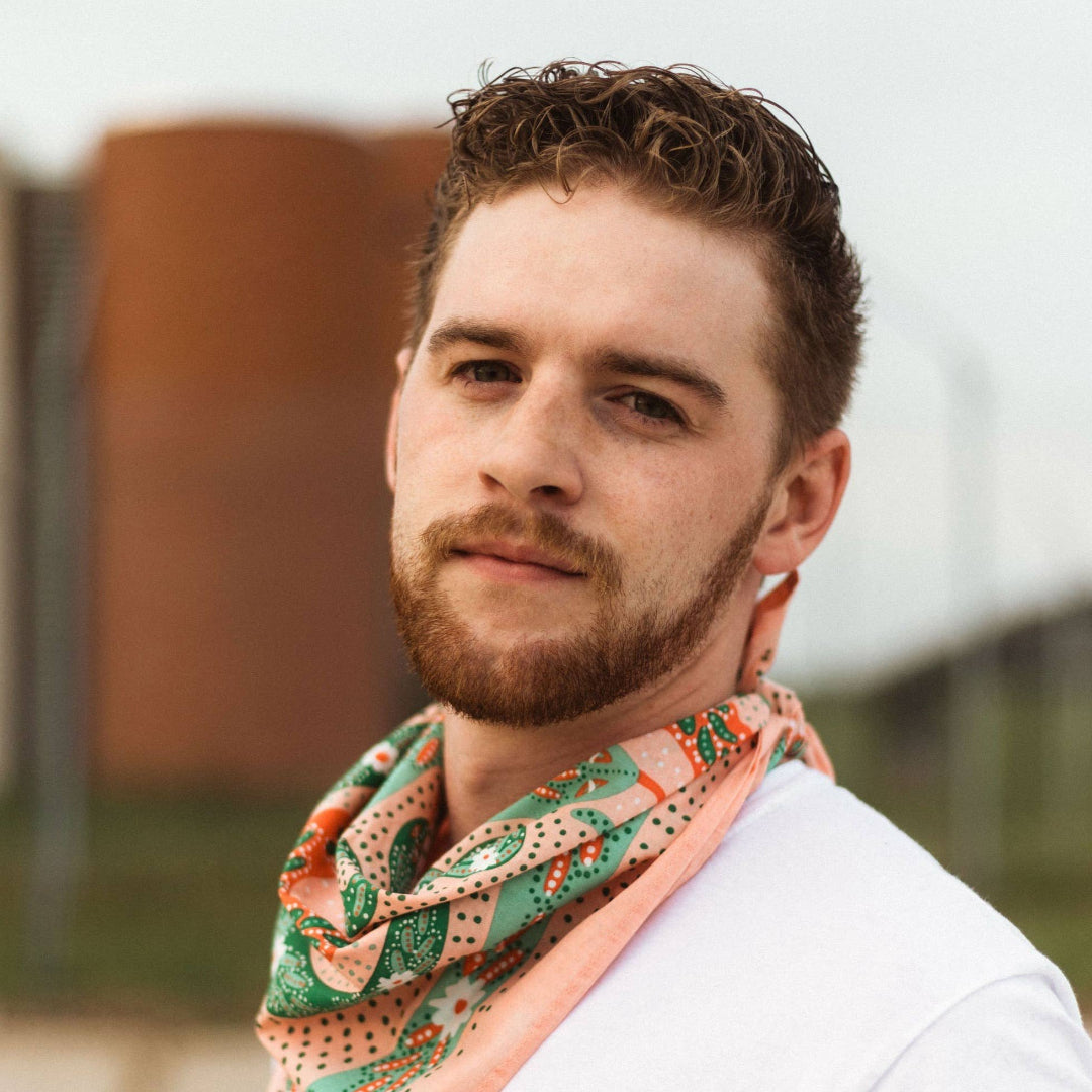 Man wearing a colorful scarf with a blurred outdoor background