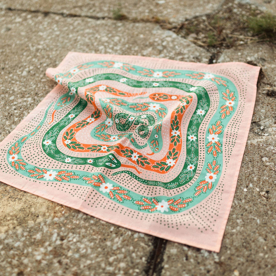Decorative handkerchief with green and orange patterns on a concrete surface