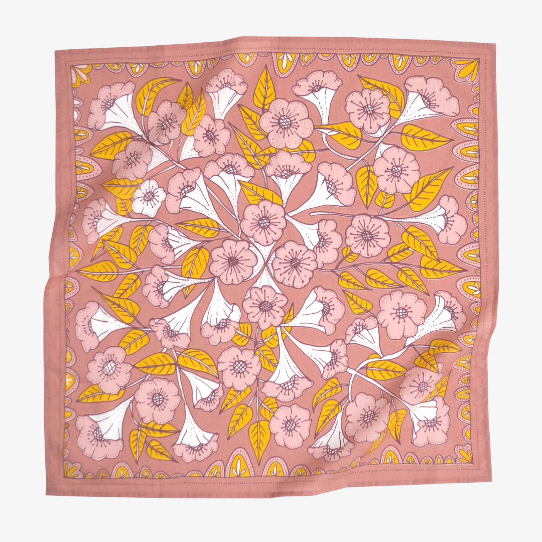 A pink bandana with a floral pattern. The pattern features white flowers with yellow centers and green leaves.