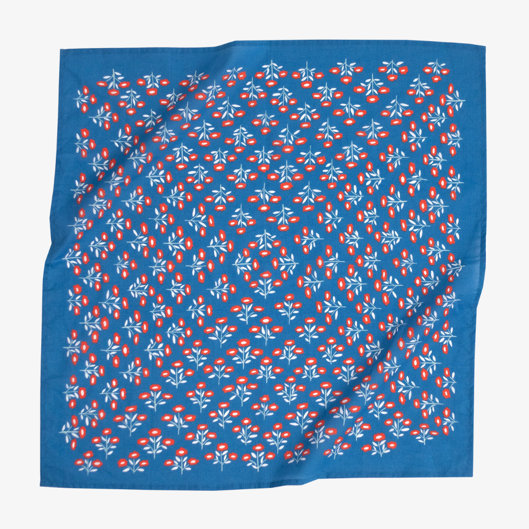 A blue bandana with a floral pattern. The pattern features small red flowers with white centers and white leaves.