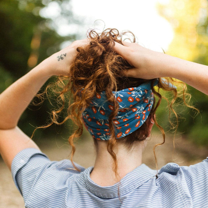 A blue bandana with a floral pattern. The pattern features small red flowers with white centers and white leaves.