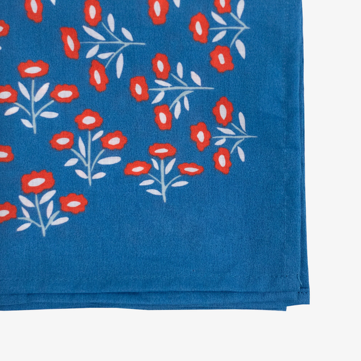 A blue bandana with a floral pattern. The pattern features small red flowers with white centers and white leaves.
