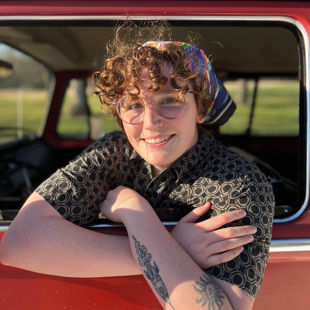 A black bandana featuring a pattern of overlapping Pride flags in various colors and designs. The flags include the classic rainbow flag, the transgender flag, and the bisexual flag.