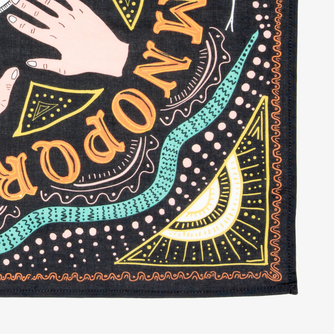A black bandana with a mystical pattern. The pattern features a Ouija board design with hands pointing to letters and numbers, along with celestial symbols like moons and stars.