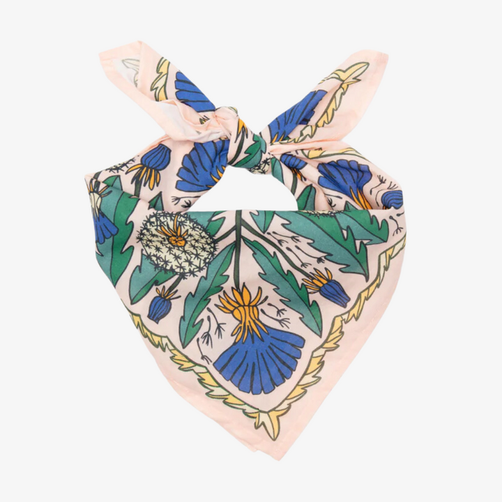 A pink bandana with a floral pattern. The pattern features blue and yellow dandelions with green leaves. The border of the bandana has a decorative, repeating pattern.