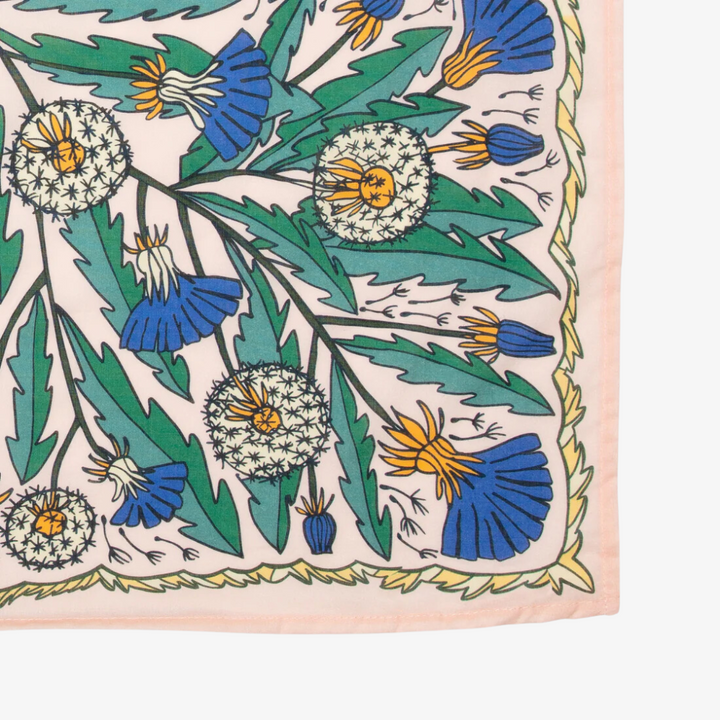 A pink bandana with a floral pattern. The pattern features blue and yellow dandelions with green leaves. The border of the bandana has a decorative, repeating pattern.