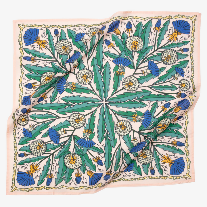 A pink bandana with a floral pattern. The pattern features blue and yellow dandelions with green leaves. The border of the bandana has a decorative, repeating pattern.