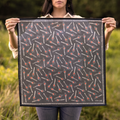 Person holding a black fabric with red and white pattern in a grassy outdoor setting