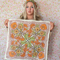 Woman holding a floral patterned fabric against a floral wallpaper background