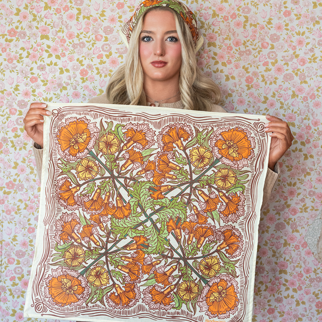 Woman holding a floral patterned fabric against a floral wallpaper background