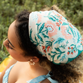 Person wearing a floral headscarf with a blurred green background