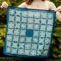 Person holding a blue fabric with white floral patterns against a green leafy background