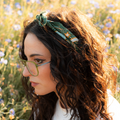 Woman with a green headband and glasses in a field of flowers