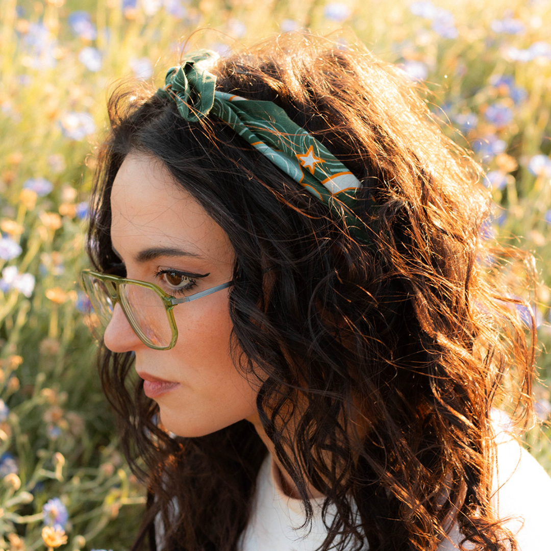 Woman with a green headband and glasses in a field of flowers