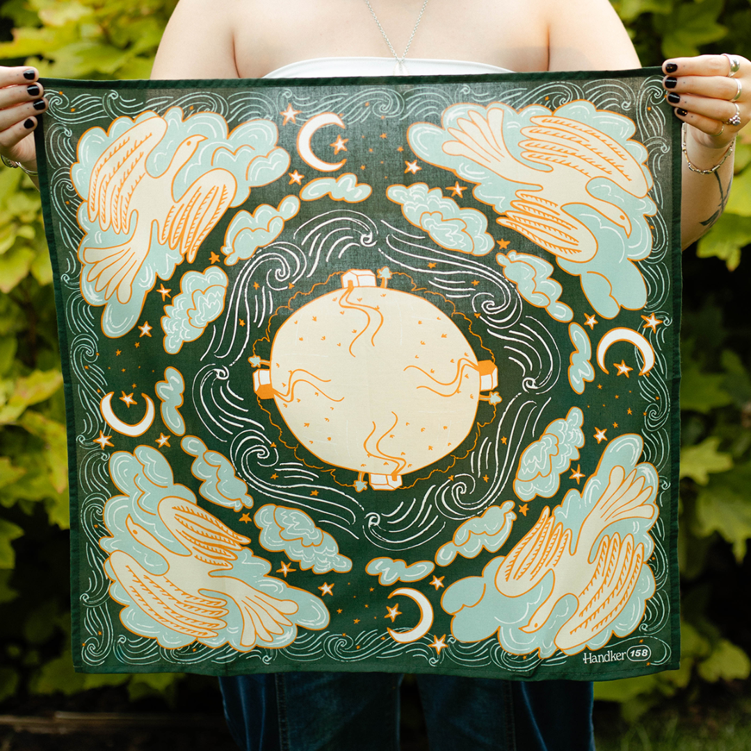 Person holding a decorative fabric with celestial design featuring angels, clouds, and stars.