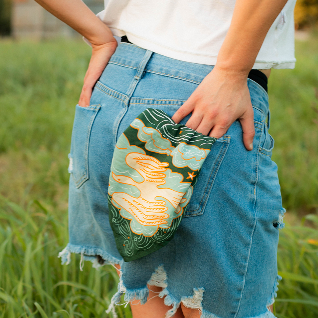 Person wearing denim shorts with a floral patch in a grassy outdoor setting