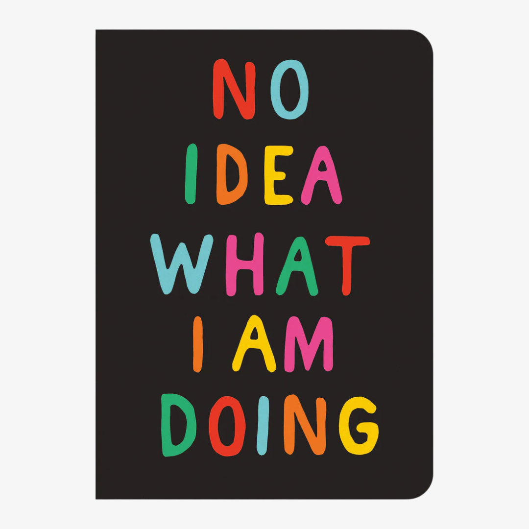 A black notebook with the text "NO IDEA WHAT I AM DOING" printed on it in colorful letters.