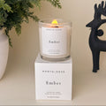 North+Rose Ember candle on a box with a plant and black deer figurine in the background