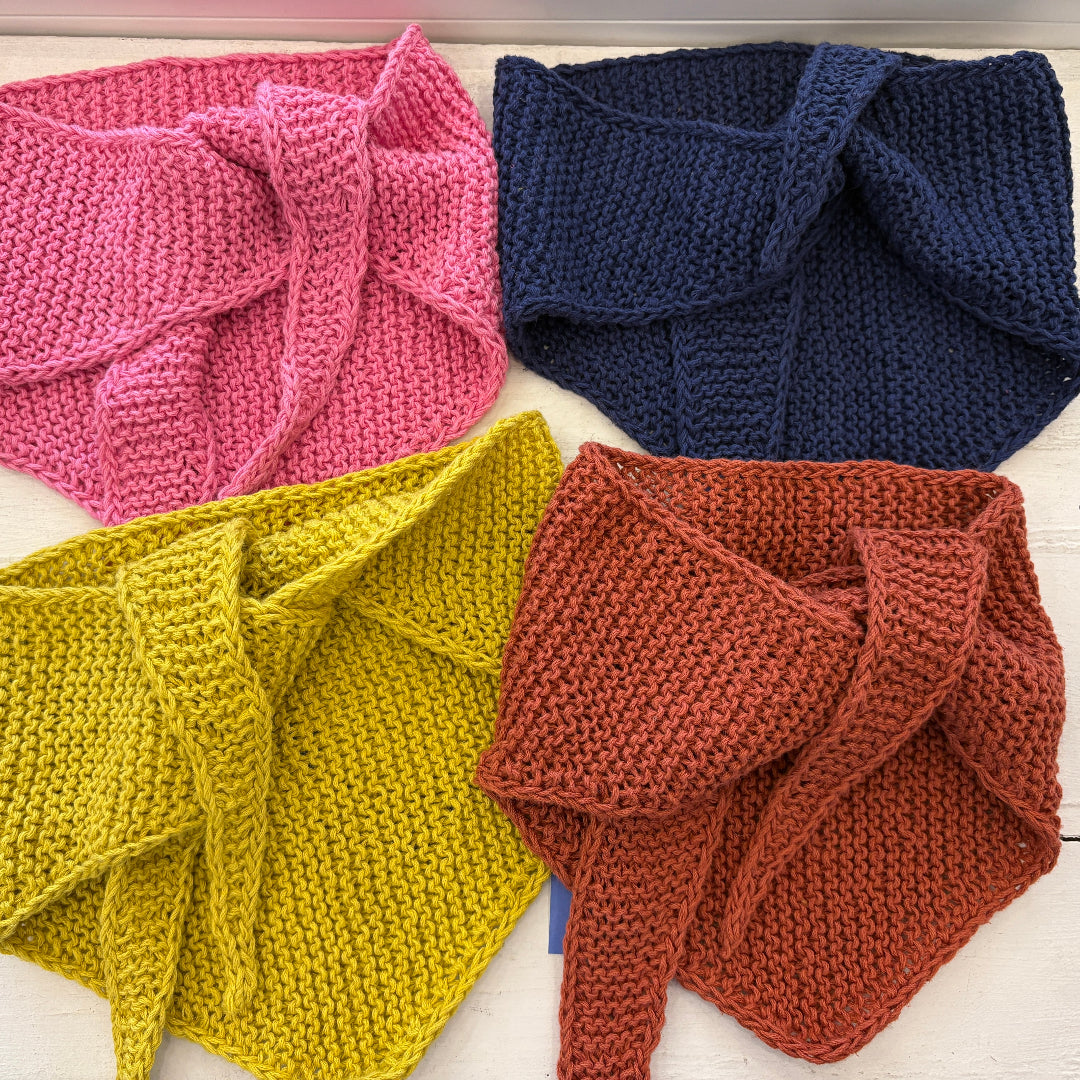 Four knitted scarves in pink, blue, yellow, and brown on a white surface.
