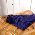 Purple knitted item on a wooden surface with a white background