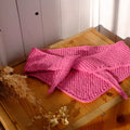 Pink knitted fabric on a wooden surface with a white background